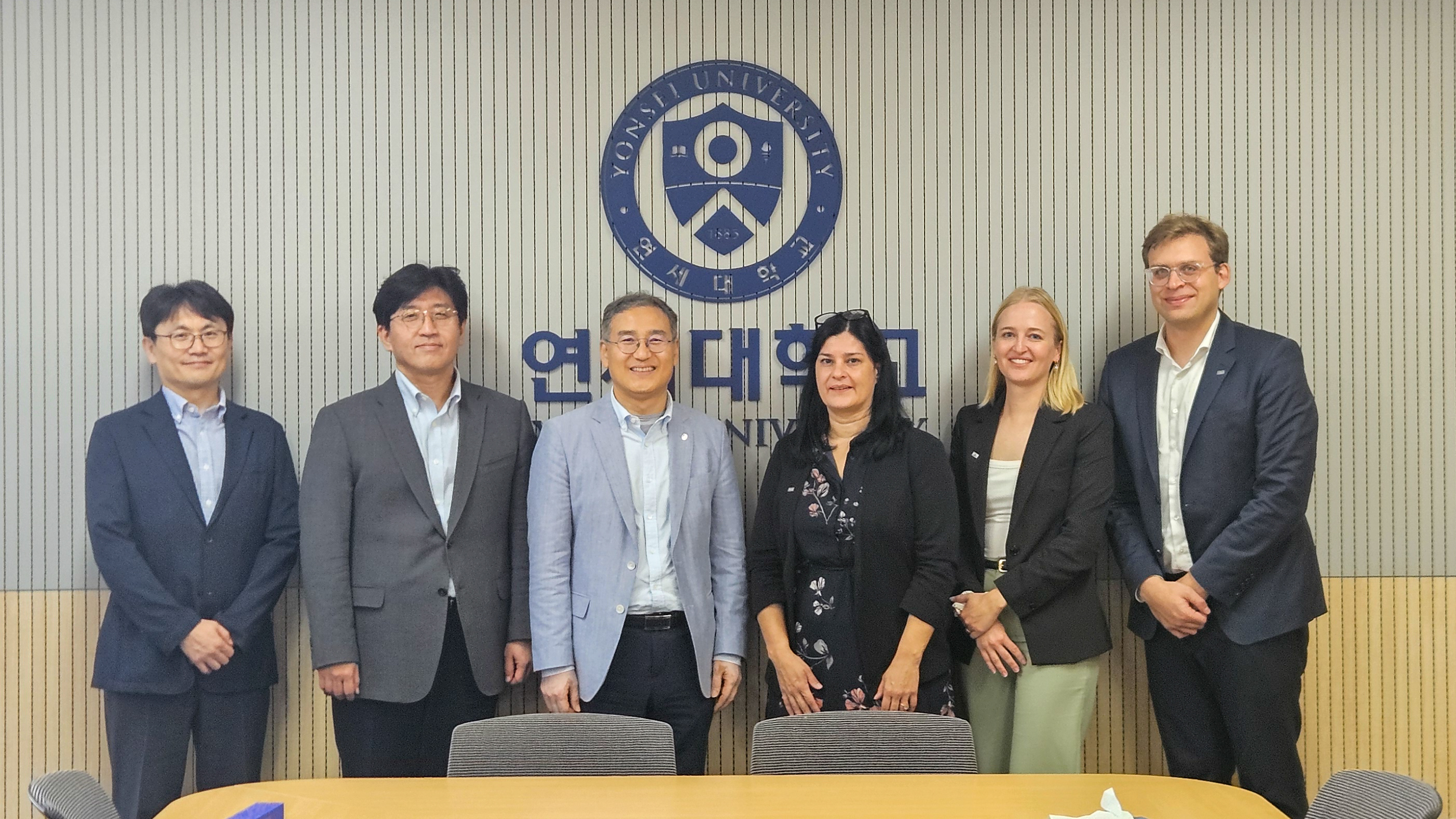 Swiss and Japanese university representatives in a group picture in front of Yonsei University logo.