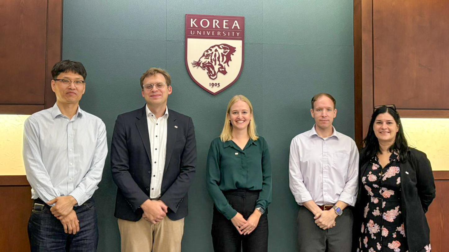Swiss and Japanese university representatives in a group picture in front of Korea University logo.